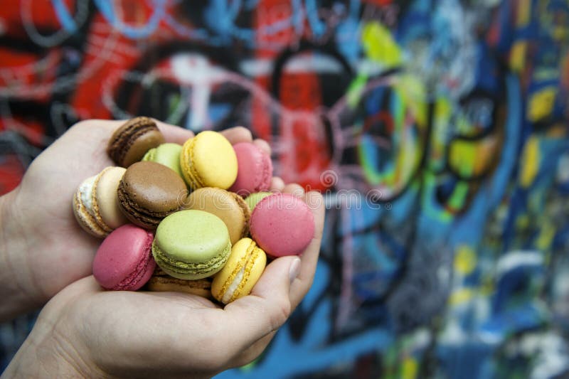 Manos que sostienen la pila de galletas coloridas de los macarrones fotografía de archivo Manos que sostienen la pila de galletas coloridas de los macarrones fotografía de archivo