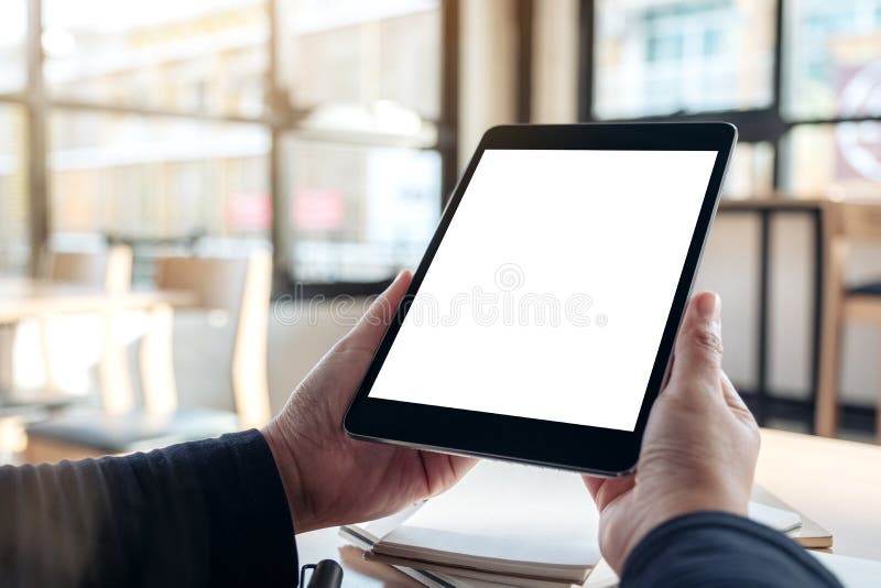 Manos que sostienen y que usan la PC negra de la tableta con la pantalla de escritorio blanca del espacio en blanco mientras que fotos de archivo libres de regalías Manos que sostienen y que usan la PC negra de la tableta con la pantalla de escritorio blanca del espacio en blanco mientras que fotos de archivo libres de regalías