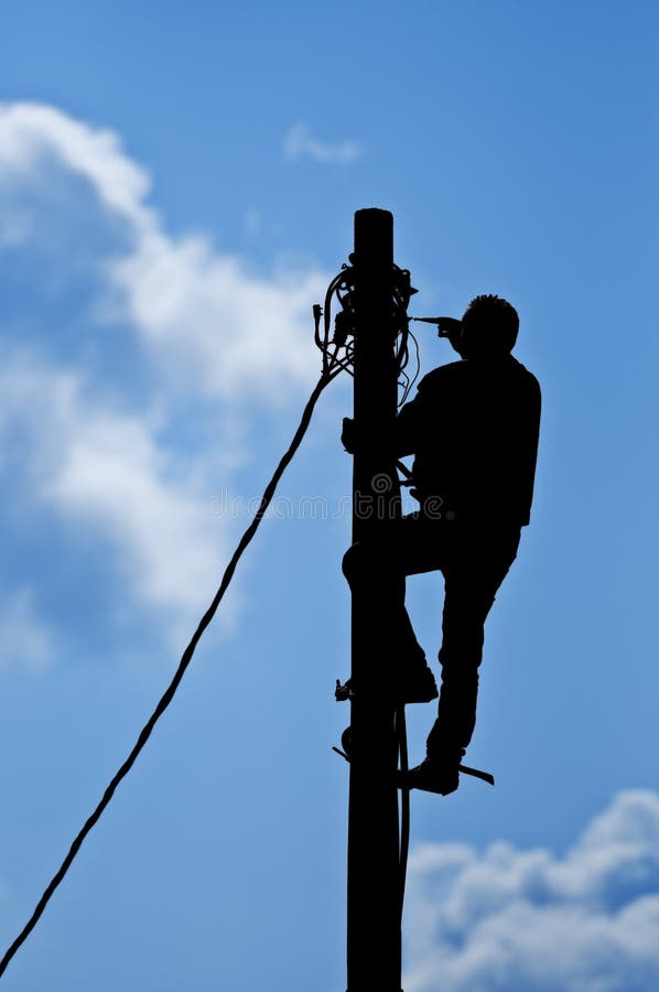 Black silhouette of man working on pole with natural sky in background. Black silhouette of man working on pole with natural sky in background