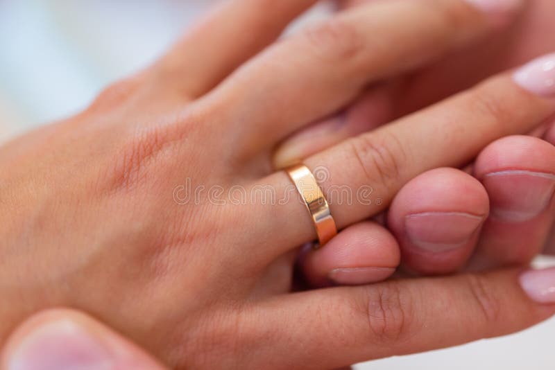 Mans Hand Putting a Wedding Ring on the Brides Finger. Stock Photo