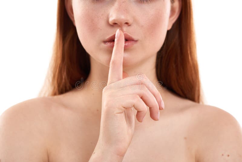 Mantendo um segredo. Foto cortada de uma jovem e atraente menina avermelhada com sardas mantendo o dedo nos lábios enquanto imagem de stock