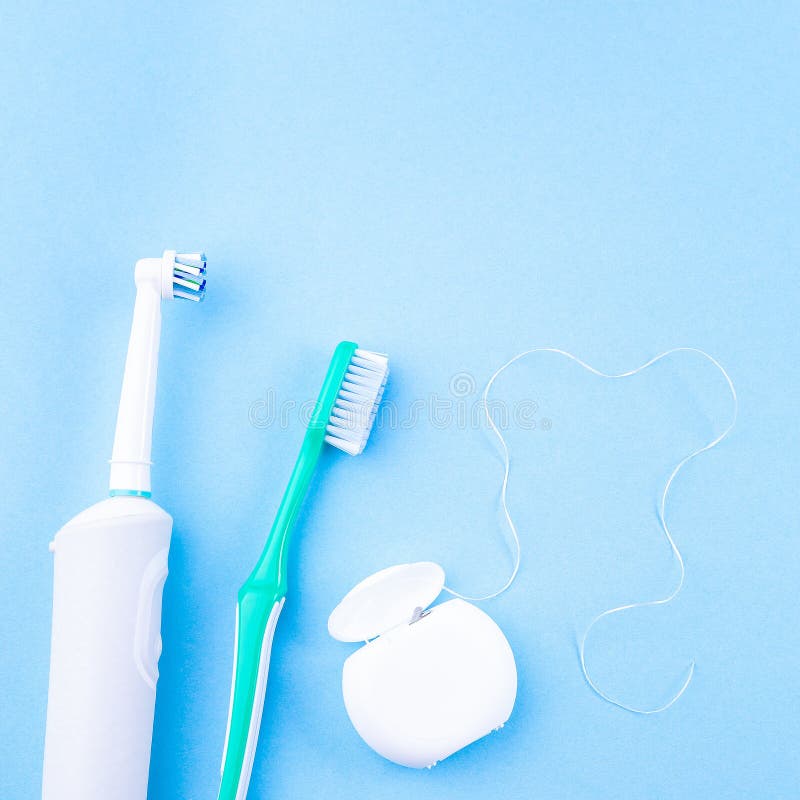 Manual toothbrush, electric toothbrush and dental floss, blue background, copy space, square format