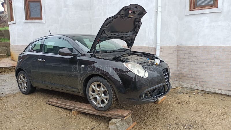 Manutenzione di un'auto - Cappuccio aperto dettagliato su un veicolo nero lucido per l'ispezione e la riparazione immagine stock