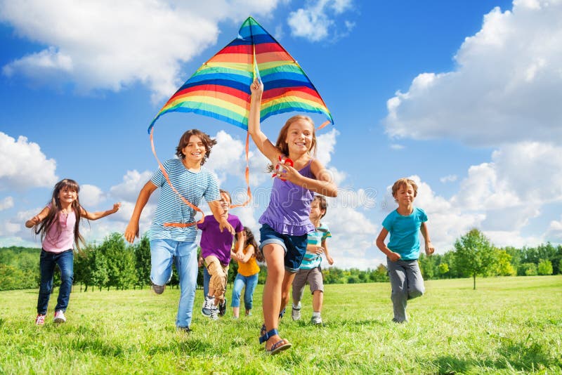 Mnoho šťastných aktivní děti, chlapce a dívky, běh s kite v parku.