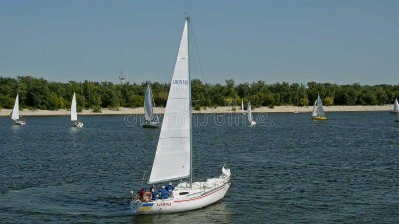 Many beautiful floating sail yachts medium size with crew , on the Dnieper River.