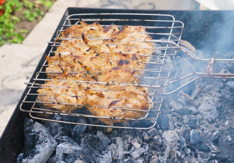 Many Chicken Roast Meat Pieces with Onion on a Grill Stock Image