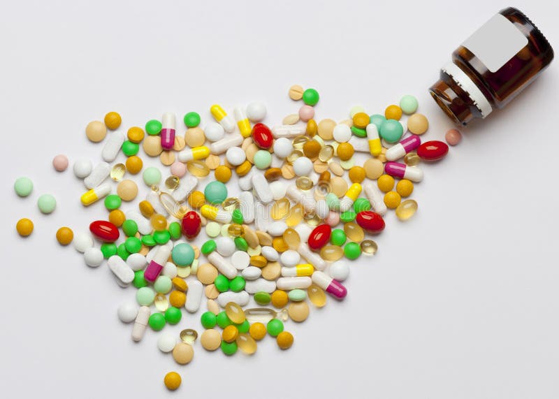 Many colorful medicines spilling out of a bottle. royalty free stock photos