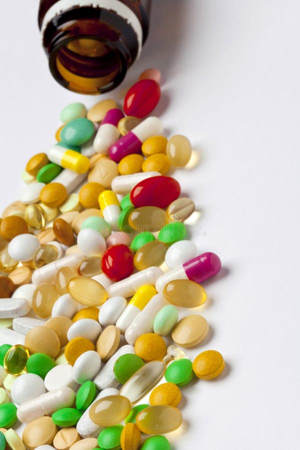 Many colorful medicines spilling out of a bottle.