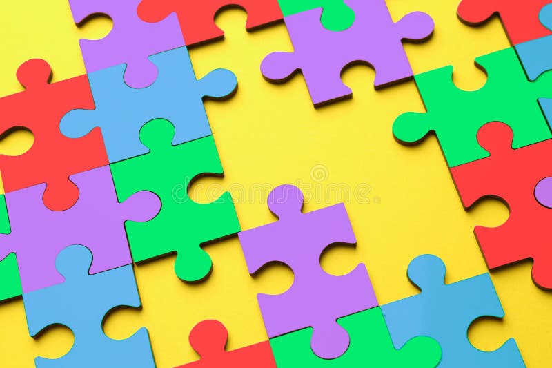Many colorful puzzle pieces on yellow background. Symbol of autism stock images
