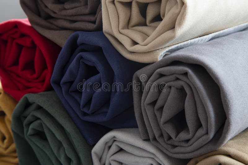 Many colorful rolls of fabric on a plain background royalty free stock photo