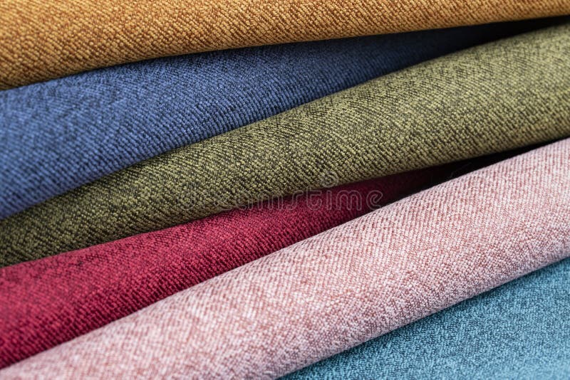 Many colorful rolls of fabric on a plain background stock images