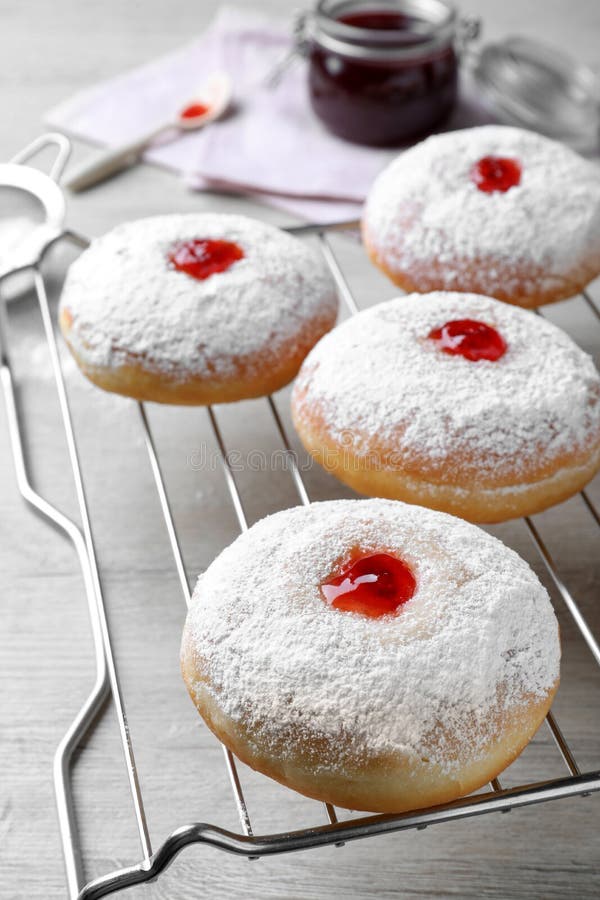 Many Delicious Donuts with Jelly and Powdered Sugar on Cooling Rack