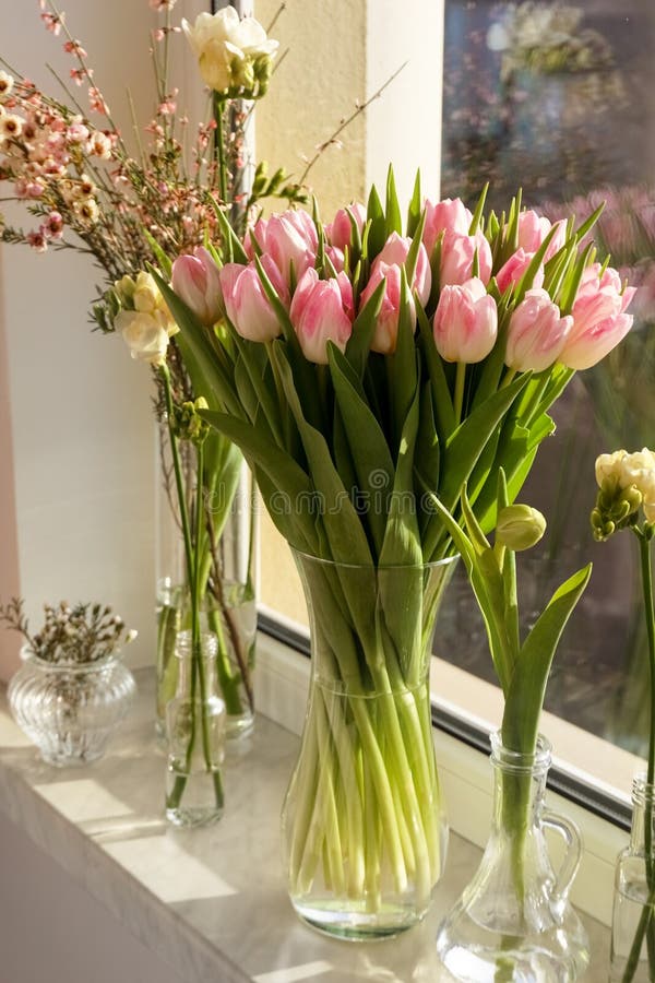 Many Different Spring Flowers and Branches with Leaves on Windowsill