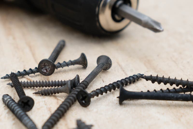 Many screws and a screwdriver on a pine board. Cordless drill with screws DIY background stock images