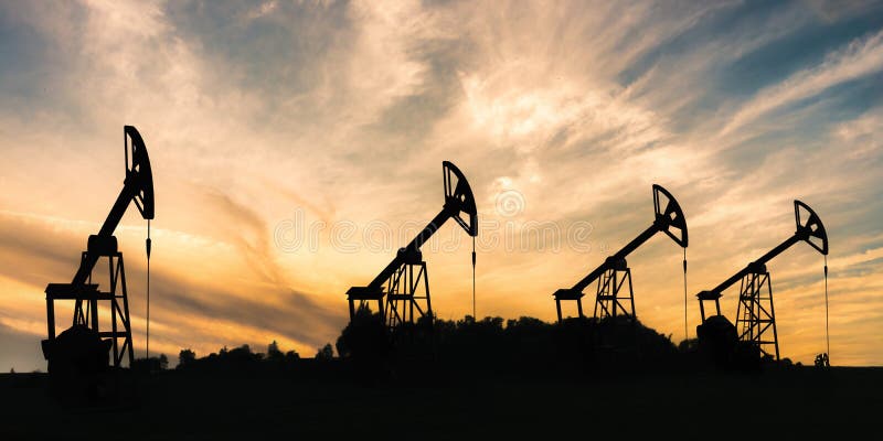 Many silhouettes of drilling oil rigs at sunset.