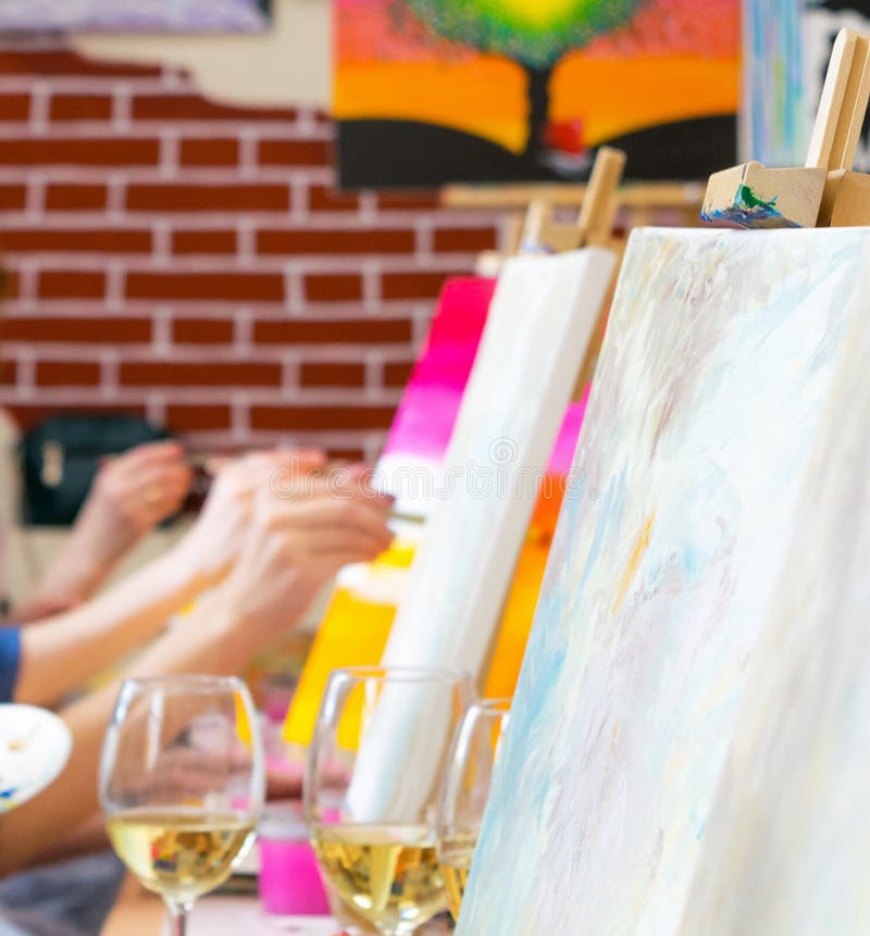 Many women of different ages drawing on canvases with brushes and drinking ...