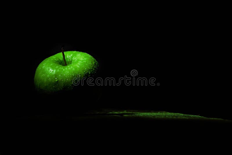 Manzana verde fría con gotas de agua en un fondo negro con luz selectiva fotos de archivo libres de regalías