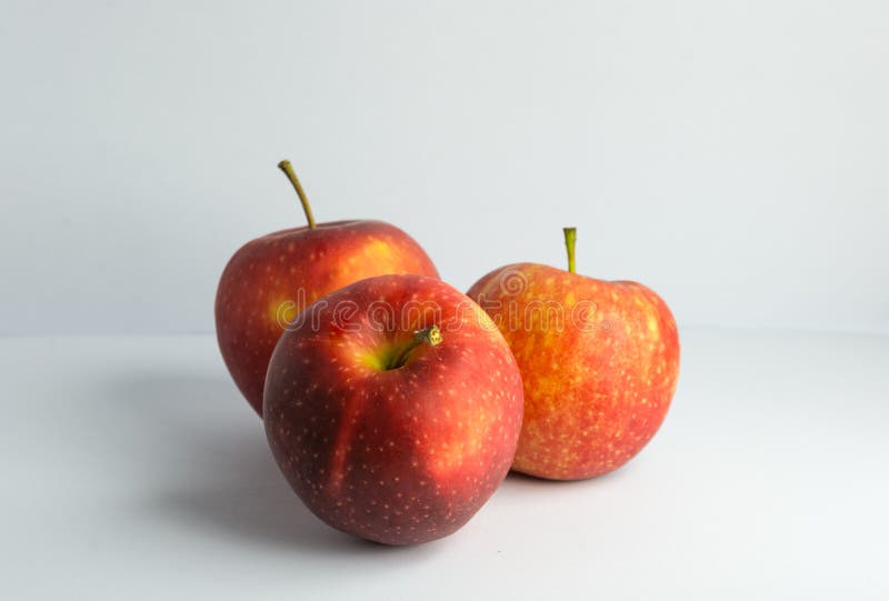 A still life style photograph of a set of three vibrantly red orange and yellow apples upon an isolated and white background. A still life style photograph of a set of three vibrantly red orange and yellow apples upon an isolated and white background.