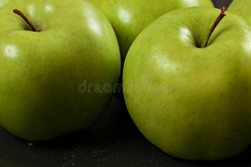 Manzanas verdes en el tablero negro - foto del primer con el detalle en textura de la piel imagen de archivo Manzanas verdes en el tablero negro - foto del primer con el detalle en textura de la piel imagen de archivo