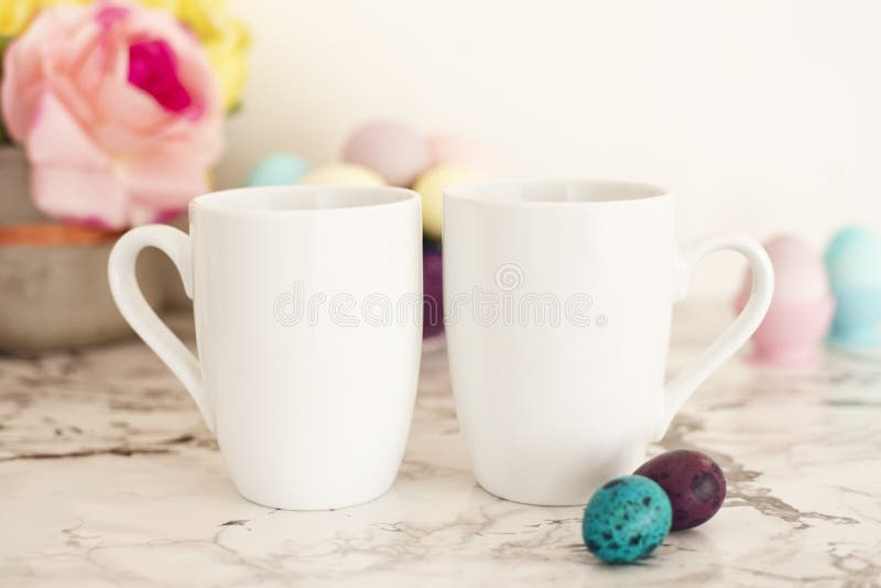 Maquette blanche de deux tasses - thème de Pâques Oeufs de pâques Oeufs colorés dans les couleurs mates Fond de marbre clair photos stock Maquette blanche de deux tasses - thème de Pâques Oeufs de pâques Oeufs colorés dans les couleurs mates Fond de marbre clair photos stock