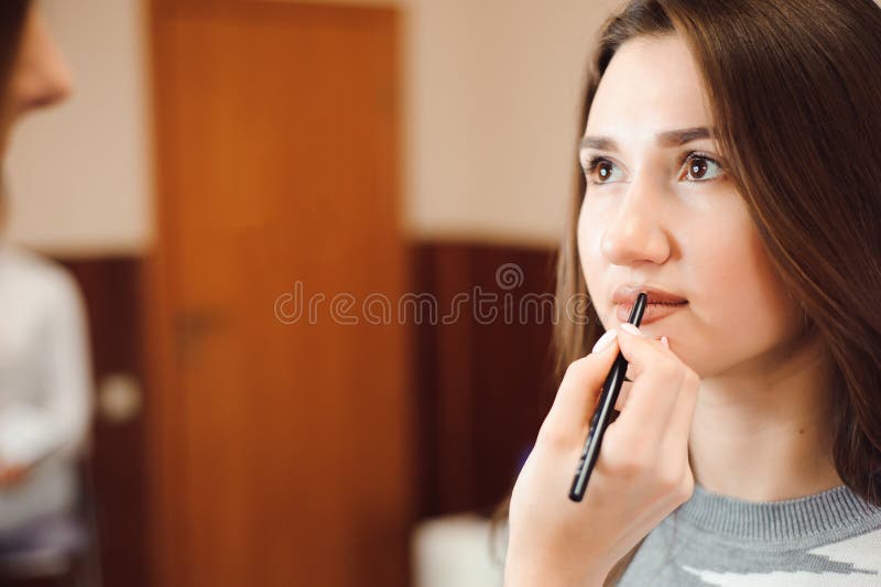 Maquilhador que cria a composição bonita para o modelo moreno foto de stock Maquilhador que cria a composição bonita para o modelo moreno foto de stock