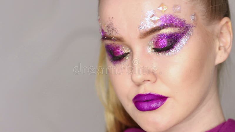 Maquillaje de la belleza Maquillaje púrpura y clavos brillantes coloridos Retrato hermoso del primer de la muchacha almacen de video