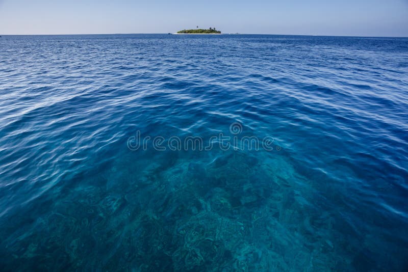 Mar azul con el arrecife de coral y pequeña isla tropical en el fondo fotografía de archivo libre de regalías Mar azul con el arrecife de coral y pequeña isla tropical en el fondo fotografía de archivo libre de regalías