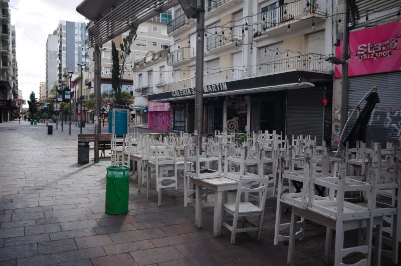 Mar del Plata, Buenos Aires, Argentina - April, 2020: Closed sidewalk cafe during lockdown on Peatonal San Martin street. Chairs placed on top of the tables before the opening of the restaurant. Mar del Plata, Buenos Aires, Argentina - April, 2020: Closed sidewalk cafe during lockdown on Peatonal San Martin street. Chairs placed on top of the tables before the opening of the restaurant