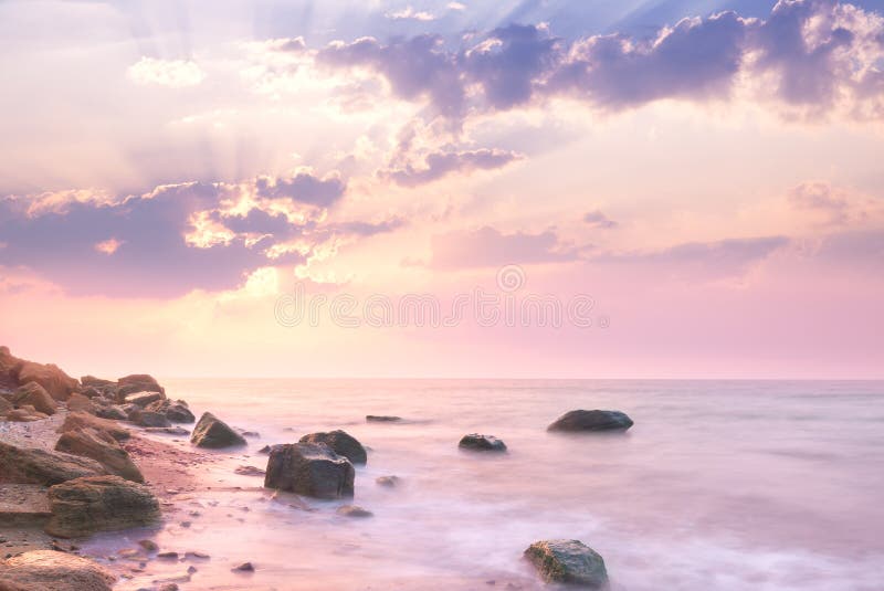 Mar - paisagem do nascer do sol sobre o litoral rochoso bonito