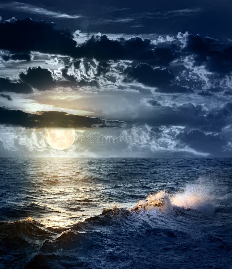 Mar tempestuoso en la noche con el cielo dramático y la luna grande