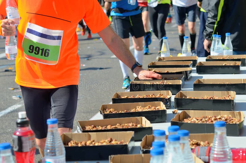 Marathonlaufenstraßenrennen, Läufer übergeben das Nehmen des Lebensmittels und Getränke auf Erfrischung zeigen, tragen, Eignung u