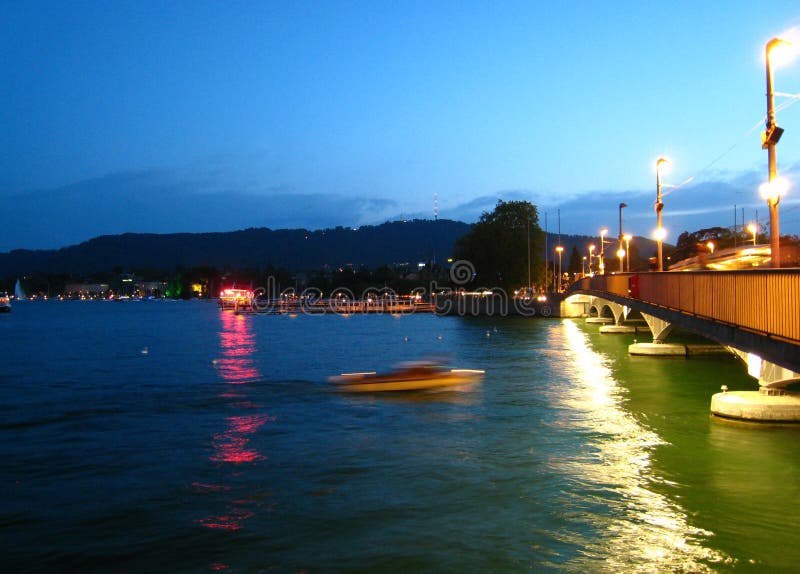 Maravillosamente vista nocturna en tiempo del verano con una lancha de carreras en el lago Zurich fotos de archivo libres de regalías Maravillosamente vista nocturna en tiempo del verano con una lancha de carreras en el lago Zurich fotos de archivo libres de regalías