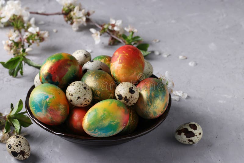 Marble Easter Eggs Painted with Multicolored Food Colors and Quail Eggs in a Plate on Gray