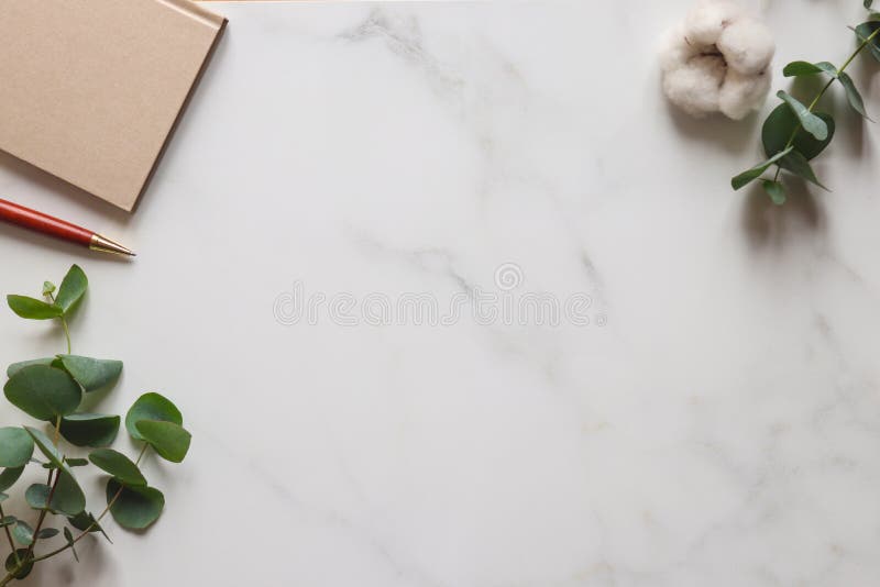 Marble minimal table desk. Eucalyptus leaves, cotton flower, notepad and pen. Template for design or invitation, copy space. Top