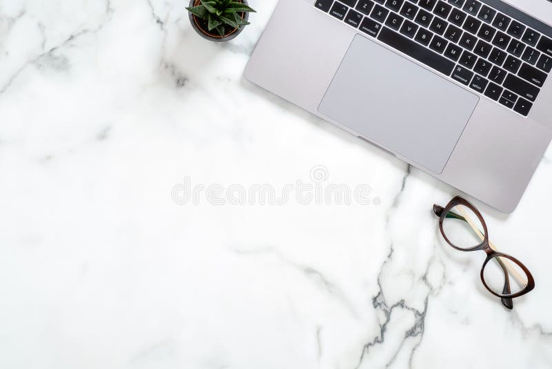 Marble office desk table with laptop computer, glasses, succulent plant. Minimal flat lay style composition, top view, overhead.