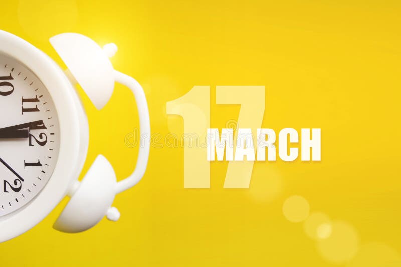 March 17th. Day 17 of Month, Calendar Date. White Alarm Clock on Yellow