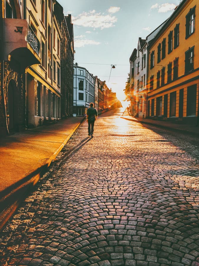 Marche de touristes d'homme dans la rue de coucher du soleil photographie stock Marche de touristes d'homme dans la rue de coucher du soleil photographie stock