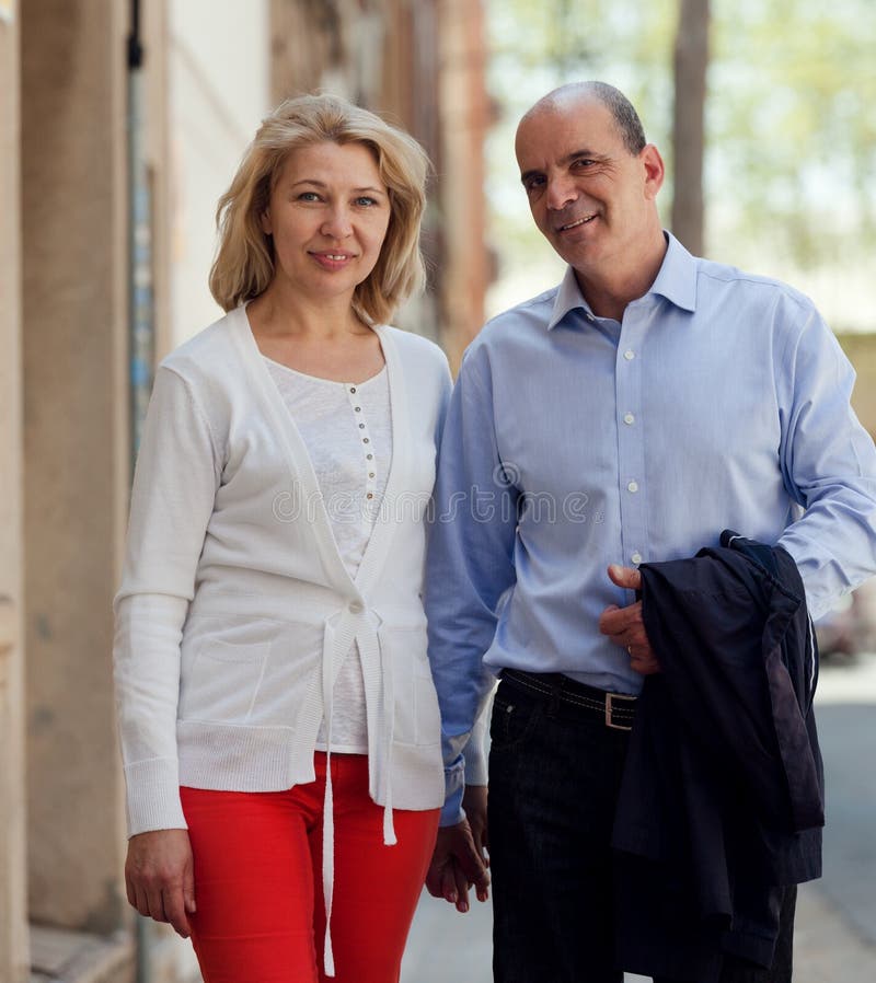 Marche par les couples supérieurs de famille de rue tenant des mains photographie stock libre de droits Marche par les couples supérieurs de famille de rue tenant des mains photographie stock libre de droits