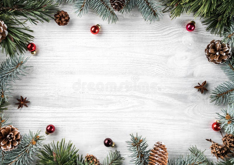 Marco creativo hecho de ramas del abeto de la Navidad en el fondo de madera blanco con la decoración roja, conos del pino Tema de