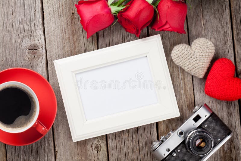 Photo frame, red roses, coffee cup and Valentines day hearts over wooden table. Top view with copy space. Photo frame, red roses, coffee cup and Valentines day hearts over wooden table. Top view with copy space