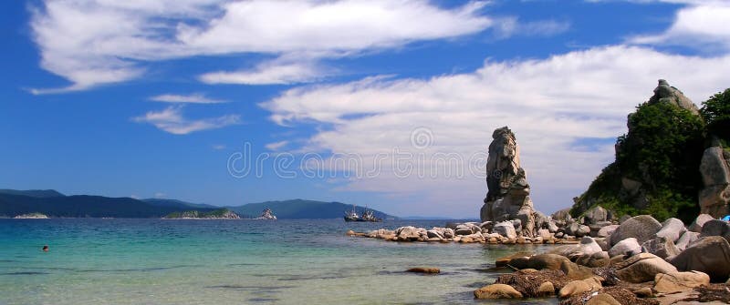 Landscape, seascape, coast of Sea of Japan, summer, blue and green seawater, stone rocks, cloudy sky, tropic, panorama. Landscape, seascape, coast of Sea of Japan, summer, blue and green seawater, stone rocks, cloudy sky, tropic, panorama