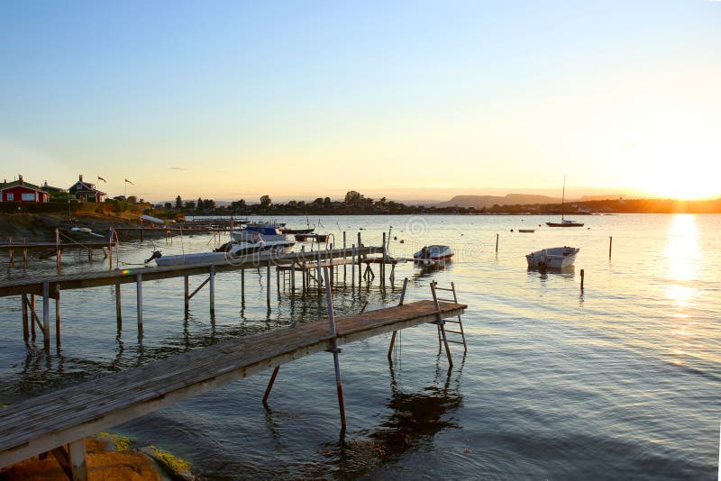 Wooden footbridges and motor boats in the marina in sunset.