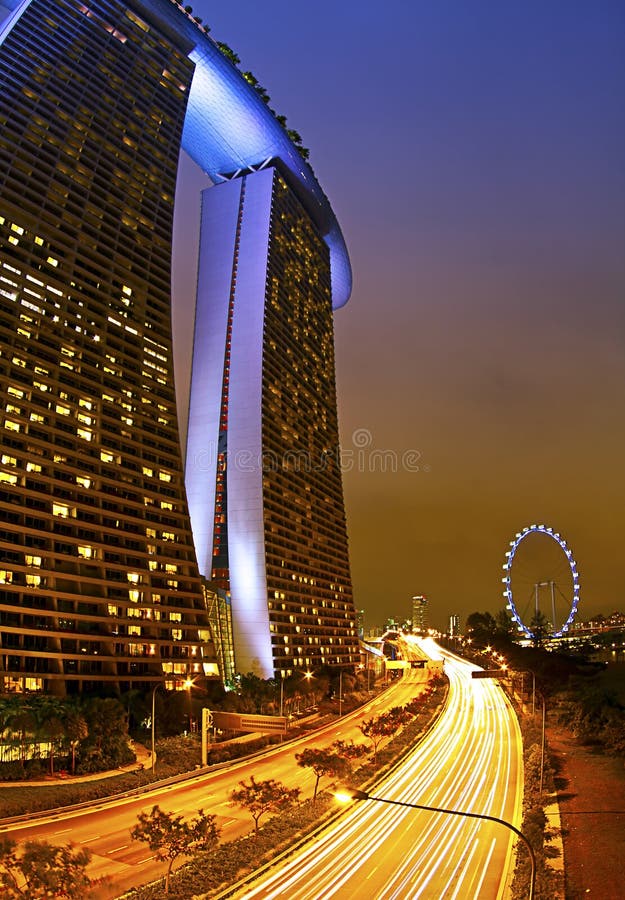 Marina Bay Sands is an integrated resort fronting Marina Bay in Singapore. Developed by Las Vegas Sands, it is billed as the world's most expensive standalone casino property at S$8 billion, including cost of the prime land. With the casino complete, the resort features a 2,561-room hotel, a 1,300,000-square-foot (120,000 m2) convention-exhibition centre, the 800,000-square-foot (74,000 m2) The Shoppes at Marina Bay Sands mall, a museum, two large theatres, seven "celebrity chef" restaurants, two floating Crystal Pavilions, an ice skating rink, and the world's largest atrium casino with 500 tables and 1,600 slot machines. The complex is topped by a 340m-long SkyPark with a capacity of 3,900 people and a 150m infinity swimming pool, set on top of the world's largest public cantilevered platform, which overhangs the north tower by 67m. The 20-hectare resort was designed by Moshe Safdie Architects. The local architect of record was Aedas Singapore, and engineering was provided by Arup and Parsons Brinkerhoff (MEP). The main contractor was Ssangyong Engineering and Construction. Originally set to open in 2009, Las Vegas Sands faced delays caused by escalating costs of material and labour shortages from the onset. The severe global financial crisis also pressured the company to delay its projects elsewhere to complete the integrated resort.[10] Although Marina Bay Sands has been compared on scale and development costs to MGM's CityCenter, the latter is a mixed-use development, with condominium properties (comprising three of the seven main structures) being sold off. The resort and SkyPark were officially opened on 23 and 24 June 2010 as part of a two-day celebration, following the casino's opening on 27 April that year. The SkyPark opened the following day. The theatres were completed in time for the first performance by Riverdance on 30 November. The indoor skating rink, which uses artificial ice, opened to a performance by Michelle Kwan on 18 December. The ArtScience Museum opened to the public and the debut of a 13-minute light, laser and water spectacle called Wonder Full on 19 February 2011 marked the full completion of the entire Integrated Resort. Marina Bay Sands is an integrated resort fronting Marina Bay in Singapore. Developed by Las Vegas Sands, it is billed as the world's most expensive standalone casino property at S$8 billion, including cost of the prime land. With the casino complete, the resort features a 2,561-room hotel, a 1,300,000-square-foot (120,000 m2) convention-exhibition centre, the 800,000-square-foot (74,000 m2) The Shoppes at Marina Bay Sands mall, a museum, two large theatres, seven "celebrity chef" restaurants, two floating Crystal Pavilions, an ice skating rink, and the world's largest atrium casino with 500 tables and 1,600 slot machines. The complex is topped by a 340m-long SkyPark with a capacity of 3,900 people and a 150m infinity swimming pool, set on top of the world's largest public cantilevered platform, which overhangs the north tower by 67m. The 20-hectare resort was designed by Moshe Safdie Architects. The local architect of record was Aedas Singapore, and engineering was provided by Arup and Parsons Brinkerhoff (MEP). The main contractor was Ssangyong Engineering and Construction. Originally set to open in 2009, Las Vegas Sands faced delays caused by escalating costs of material and labour shortages from the onset. The severe global financial crisis also pressured the company to delay its projects elsewhere to complete the integrated resort.[10] Although Marina Bay Sands has been compared on scale and development costs to MGM's CityCenter, the latter is a mixed-use development, with condominium properties (comprising three of the seven main structures) being sold off. The resort and SkyPark were officially opened on 23 and 24 June 2010 as part of a two-day celebration, following the casino's opening on 27 April that year. The SkyPark opened the following day. The theatres were completed in time for the first performance by Riverdance on 30 November. The indoor skating rink, which uses artificial ice, opened to a performance by Michelle Kwan on 18 December. The ArtScience Museum opened to the public and the debut of a 13-minute light, laser and water spectacle called Wonder Full on 19 February 2011 marked the full completion of the entire Integrated Resort.