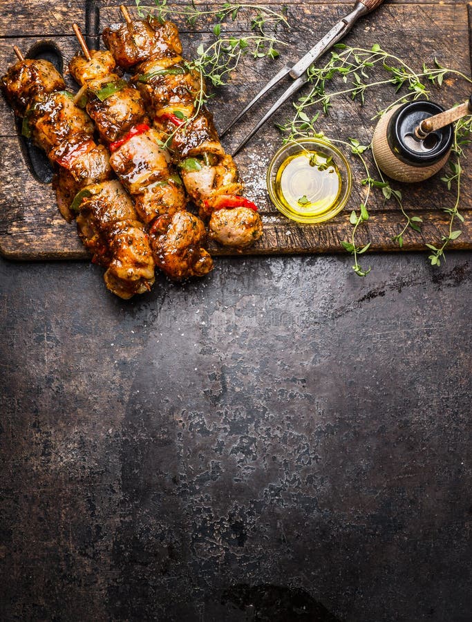 Marinated meat skewers with vegetables for grill or BBQ , fresh seasoning nad oil on dark rustic wooden background, top view