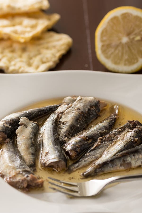 Marinated сардины в масле служили на белой плите с вилкой металла и хлебом лимона и мозоли стоковое изображение rf Marinated сардины в масле служили на белой плите с вилкой металла и хлебом лимона и мозоли стоковое изображение rf