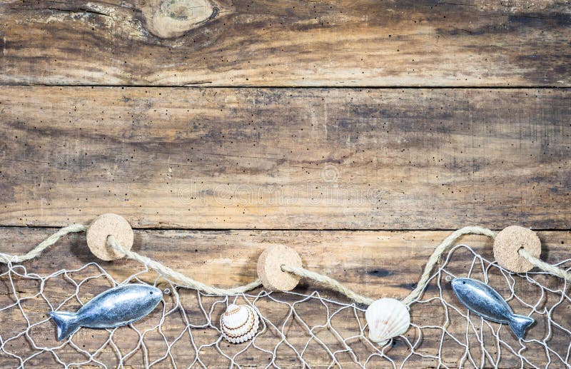 Fishing net with sea shells and fish decoration on old brown wooden boards and place for text. Fishing net with sea shells and fish decoration on old brown wooden boards and place for text.