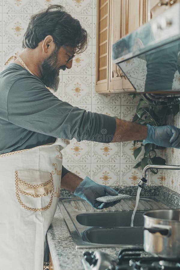 Marito un uomo che lava i piatti da solo a casa sorridendo e godendosi la pulizia domestica all'interno del tempo libero. femminil fotografie stock libere da diritti