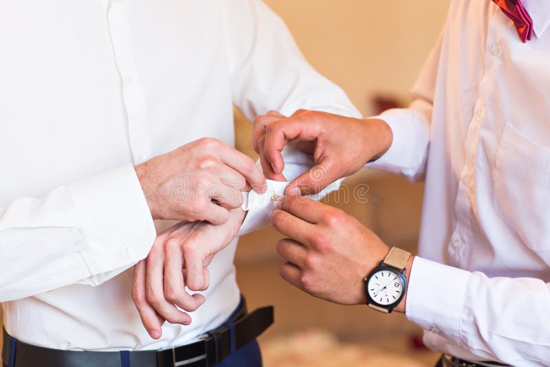 Marié d'aides de Groomsman pour mettre dessus des boutons de manchette en gros plan image libre de droits Marié d'aides de Groomsman pour mettre dessus des boutons de manchette en gros plan image libre de droits