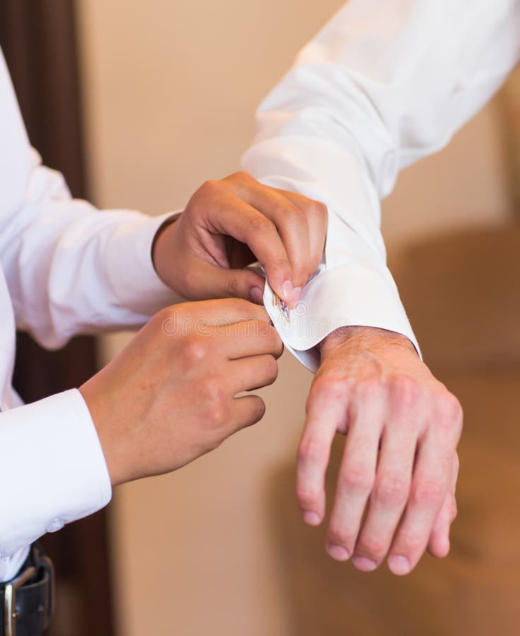Marié d'aides de Groomsman pour mettre dessus des boutons de manchette en gros plan images libres de droits Marié d'aides de Groomsman pour mettre dessus des boutons de manchette en gros plan images libres de droits