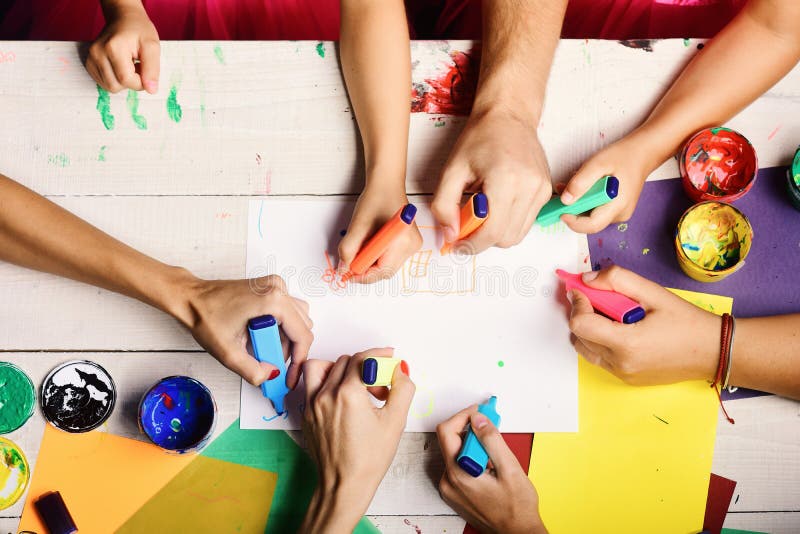 Markers in male and female hands draw on white paper